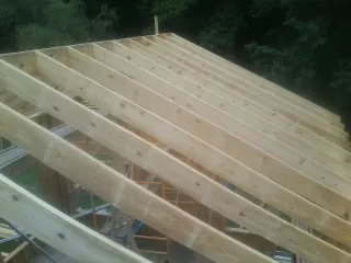 New roof rafters set over an addition before sheathing in Delhi