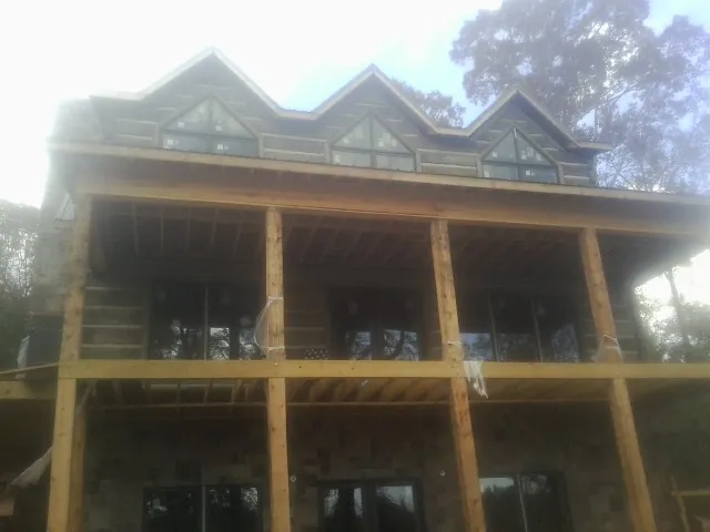 Dormers and porch framing on a large log home under construction — Roof Coating work by our crew in Delhi