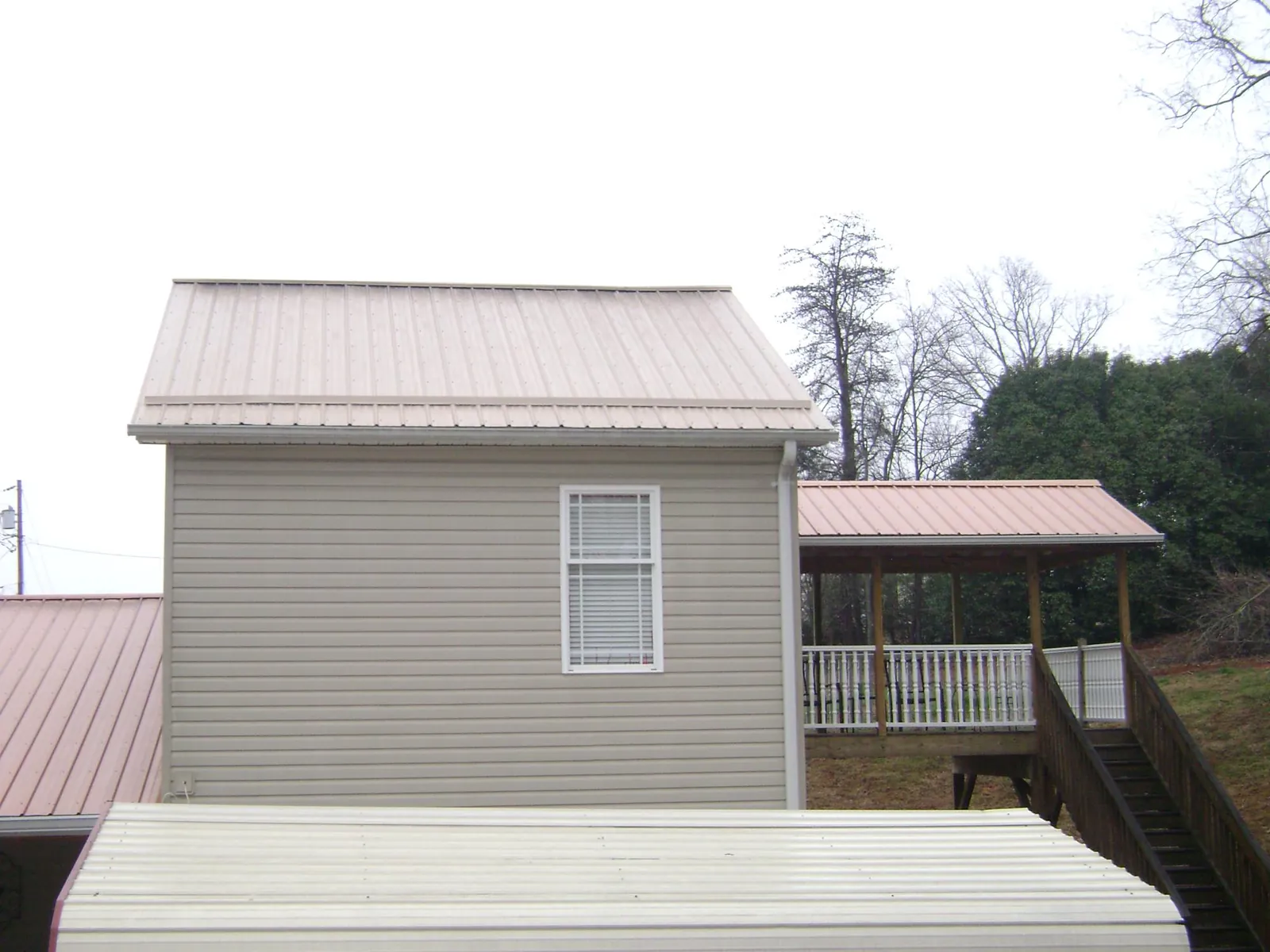 Tan metal roofs on a two story addition and attached porch, from a Roof Replacement job in Delhi